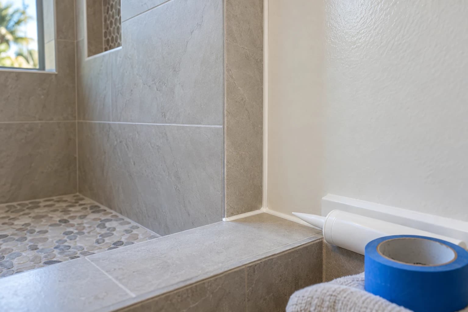 Detail of finished shower tile corner with clean caulk lines and fresh paint in a Florida bathroom ready for walkthrough
