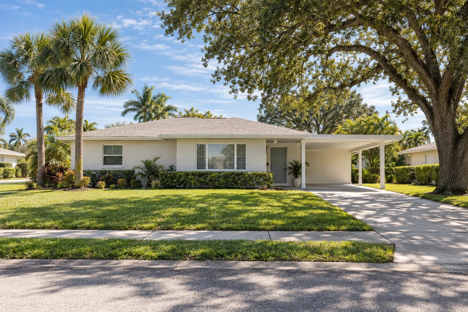 One-story mid-century block ranch home in West Bradenton with a low hip roof, a carport, and palms and a live oak in the front yard