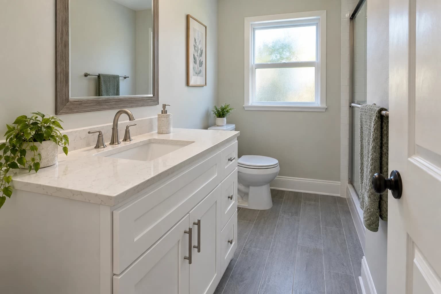 Small hall bathroom with a new white shaker vanity, a quartz top, a framed mirror, and gray plank-look floor tile