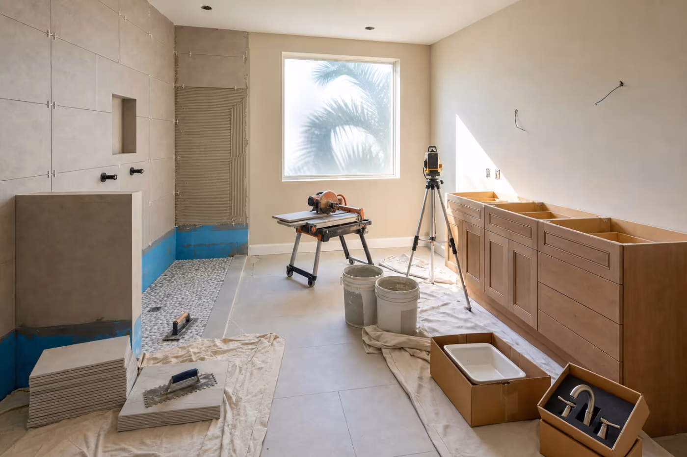 In-progress bathroom remodel in a Florida home with tiled shower walls underway, vanity rough-in staged, and professional tools neatly set aside