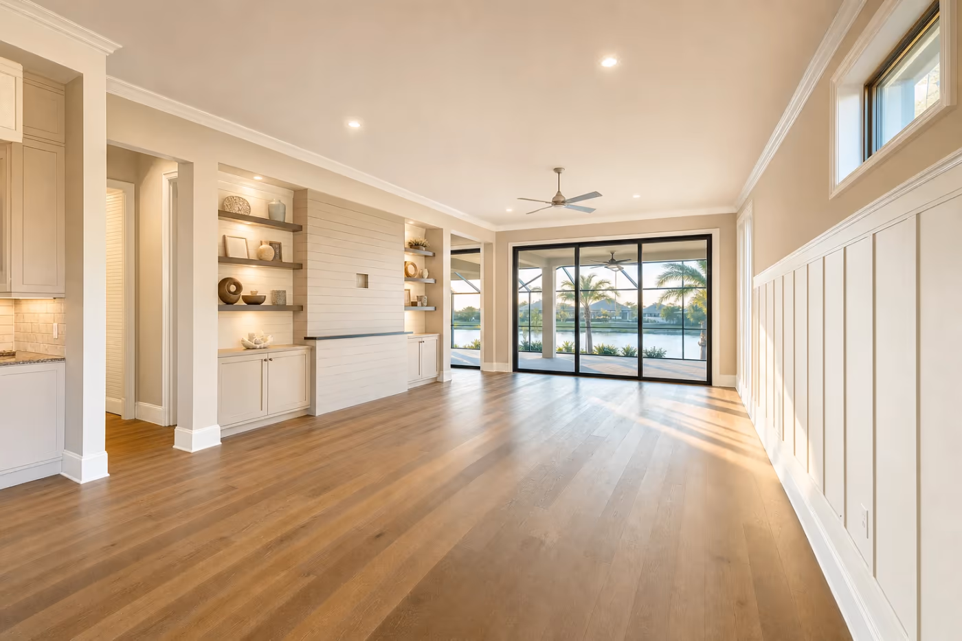 Wide view of a finished Florida great room showcasing crown molding, wainscoting, and built-in shelving in bright coastal light