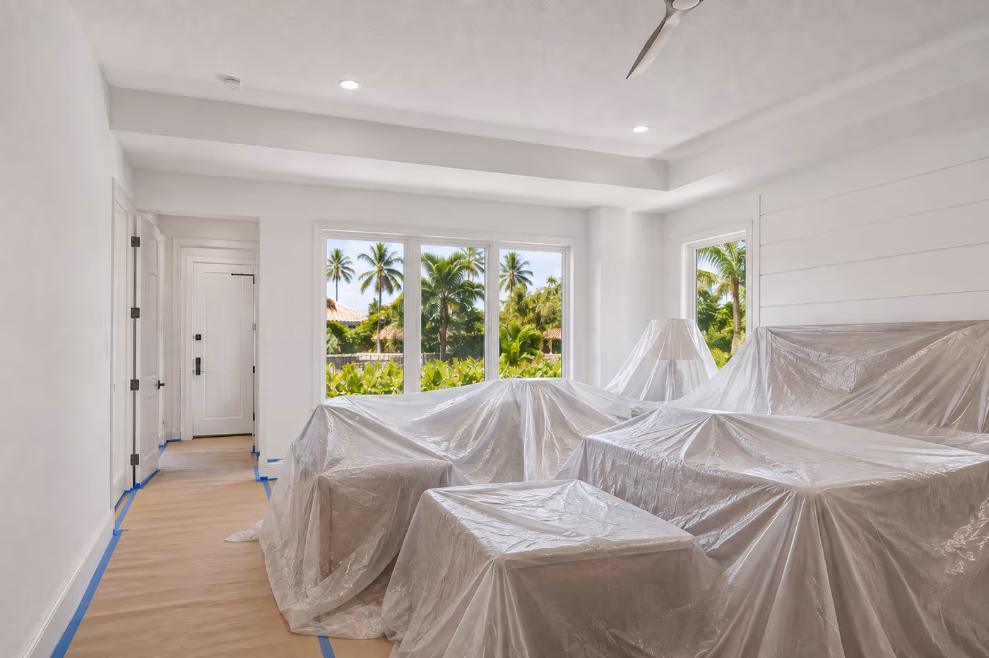 Furniture covered in plastic sheeting in a Florida room prepped for drywall and paint work