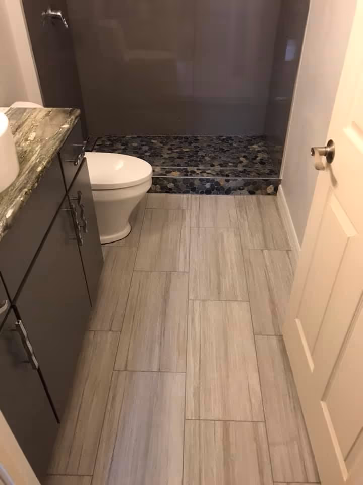 Bathroom remodel with a pebble tile shower entry and plank tile flooring