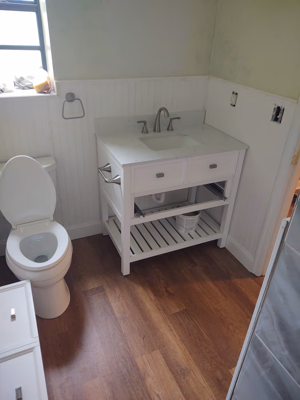 Remodeled bathroom with a new vanity, beadboard walls, and wood flooring