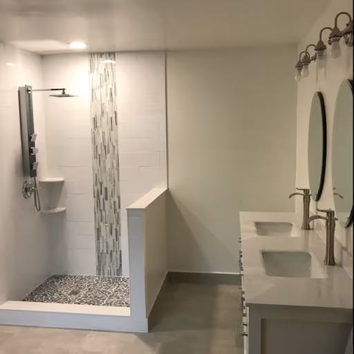 Remodeled bathroom with a walk-in rain shower, pebble floor, and double vanity
