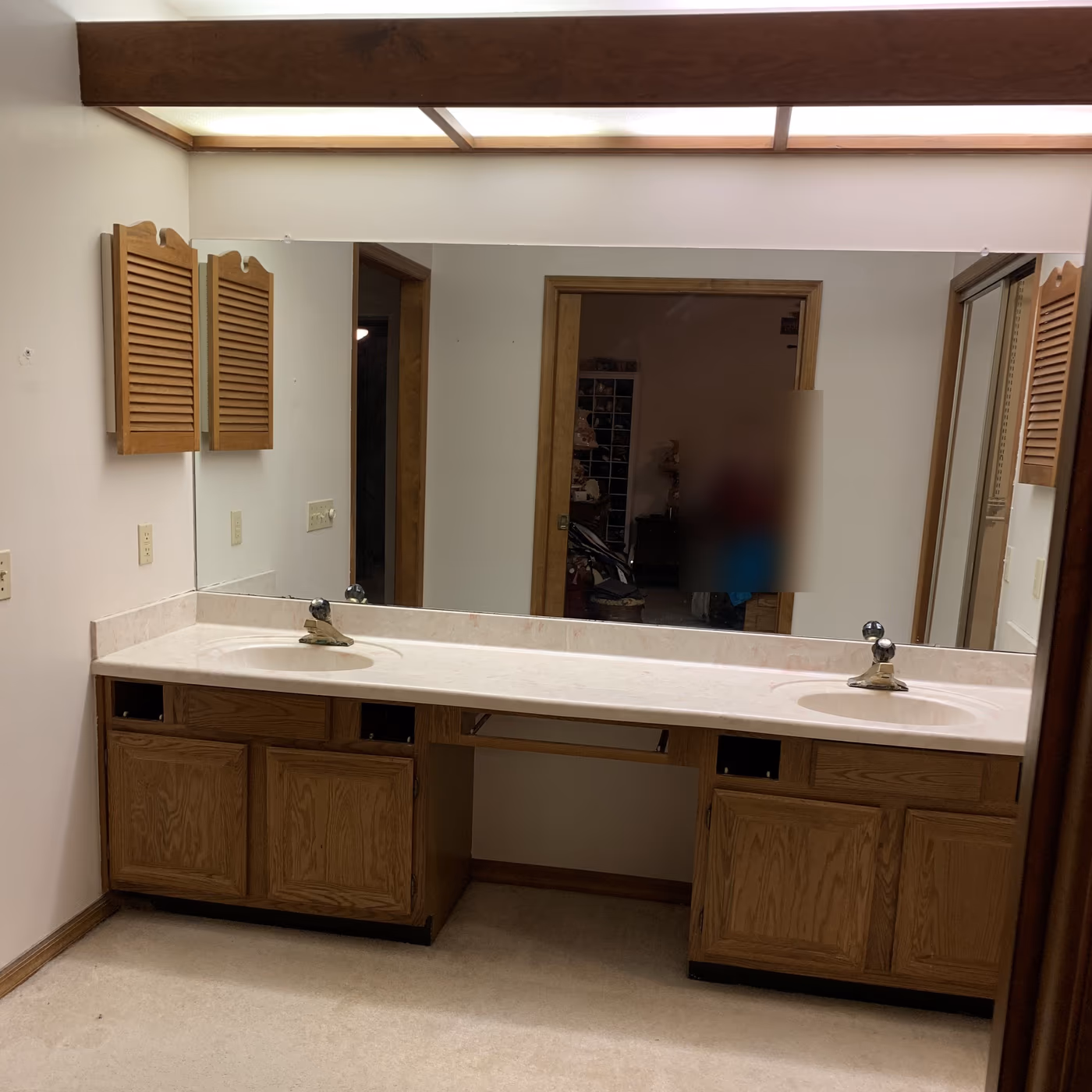 Dated oak double vanity with a cultured marble top and carpeted bathroom floor before the remodel
