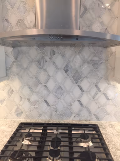New marble mosaic kitchen backsplash installed behind a gas cooktop