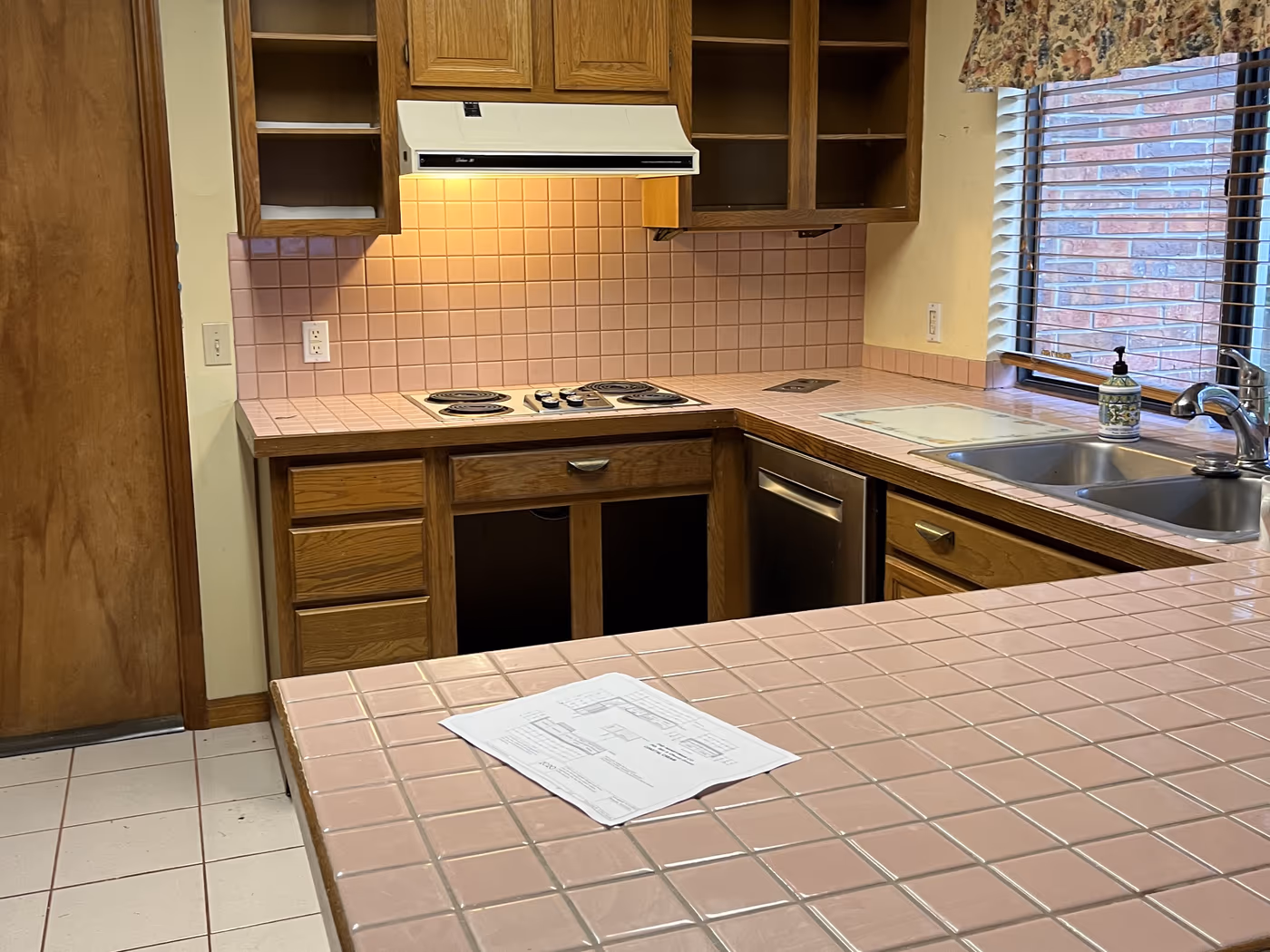 Dated kitchen with oak cabinets and pink tile counters before the remodel