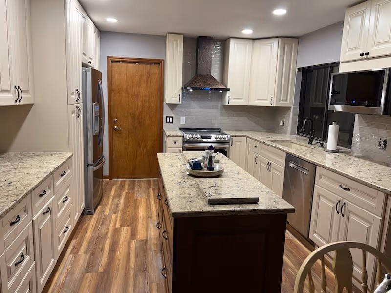 Remodeled kitchen with white cabinets, quartz counters, and a wood island