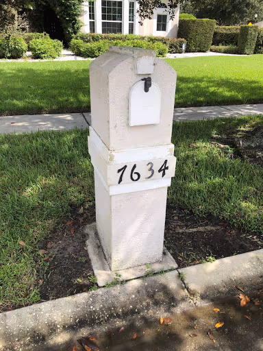 Weathered stucco mailbox pillar with stains and worn paint