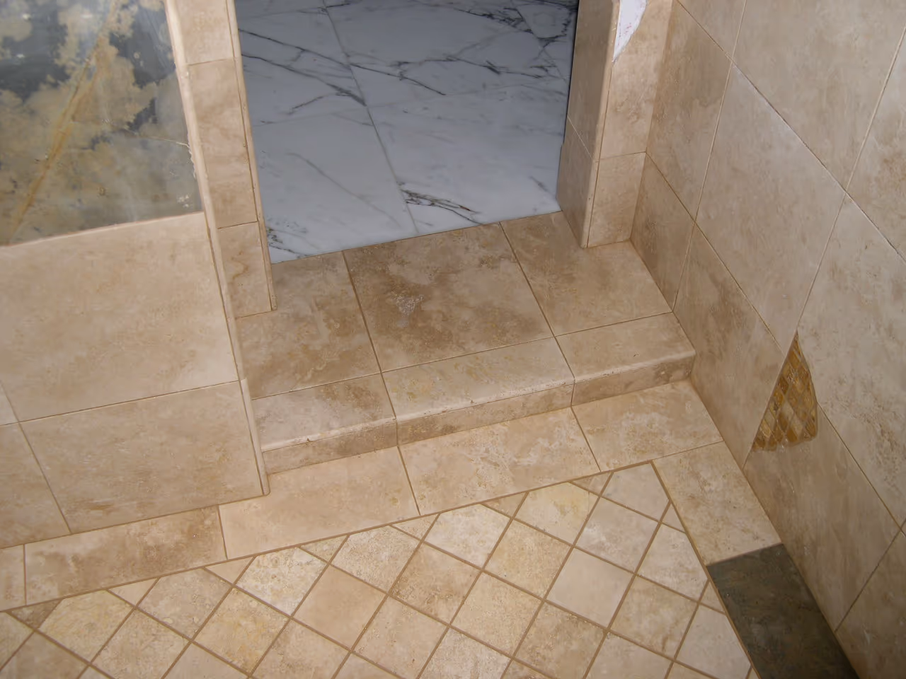 Travertine tile floor with a diamond-set inlay and finished step