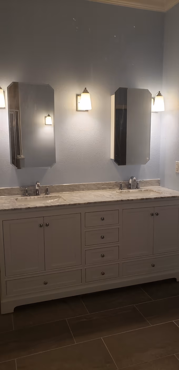 New white double vanity with stone counter and updated lighting