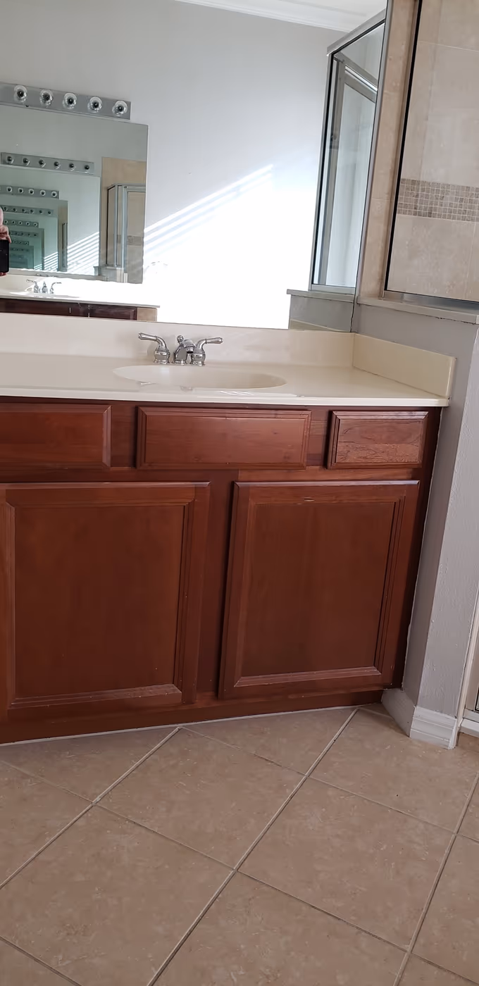 Old single-sink vanity with dated cabinets before the remodel
