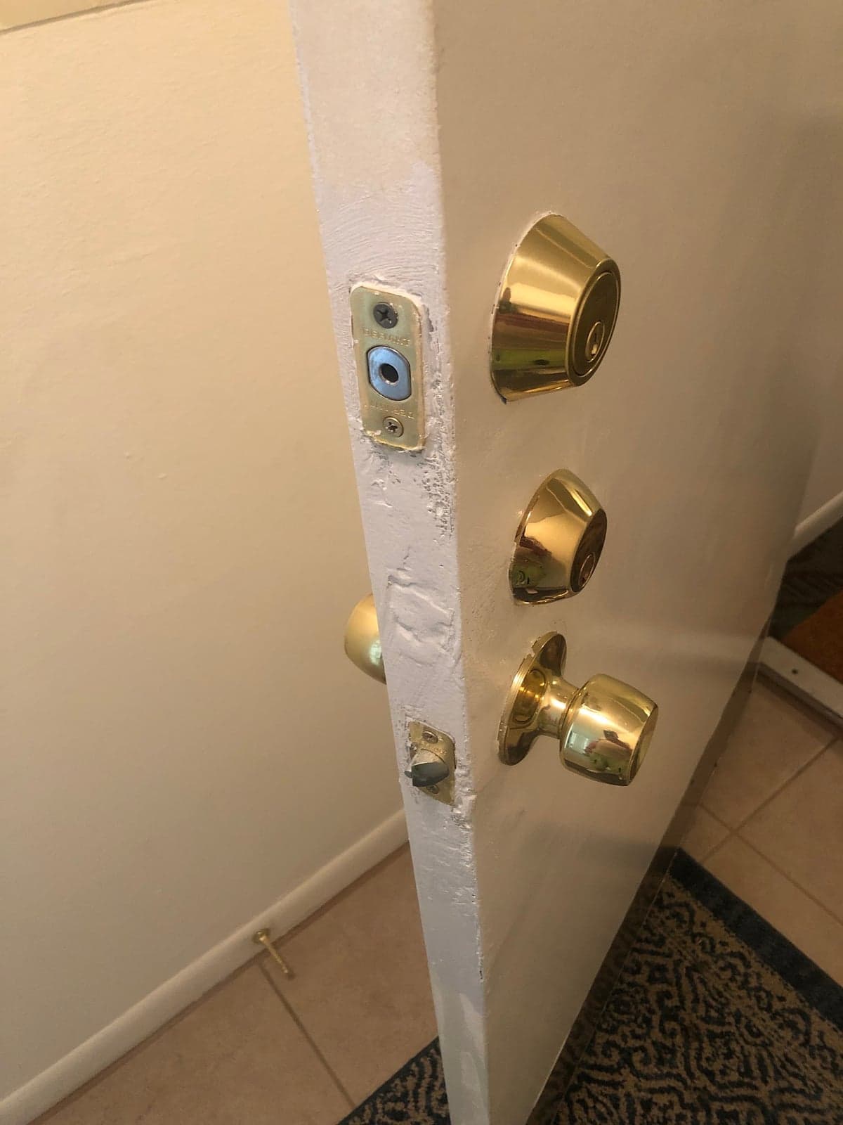 Edge of a white entry door with a rebuilt jamb, a new brass deadbolt, and a new knob set