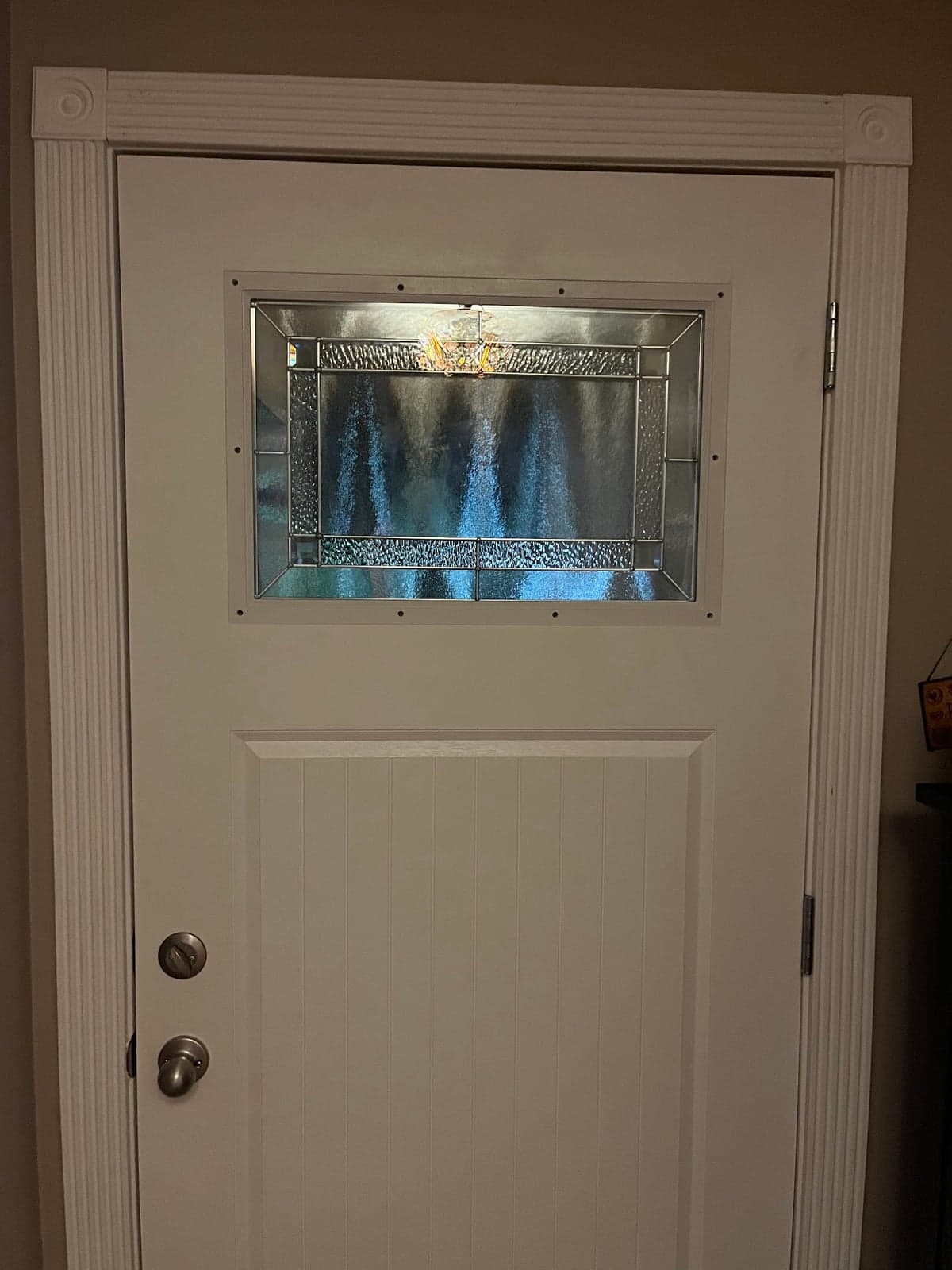 White exterior door with a decorative stained glass insert set in new fluted trim